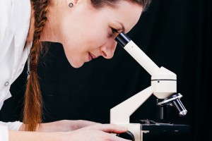 Profile of a beautiful science student looking into a microscope in a laboratory